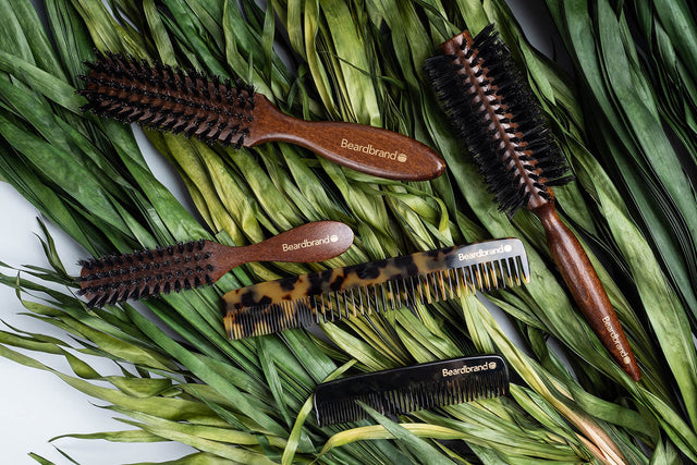 Beardbrand Beard Combs and 100% Boar's Hair Beard Brushes artistically arranged on thick, green grass.  