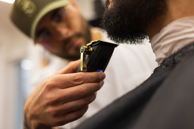 A close-up of a barber shaping a client’s beard with electric clippers, focusing on detail and craftsmanship.