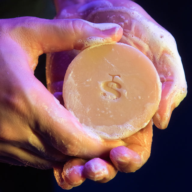 A person sudsing up a Beardbrand Old Money Utility Bar in their hands.