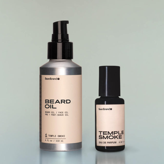 A bottle of Temple Smoke Beard Oil and Temple Smoke Eau de Parfum against a grey background.