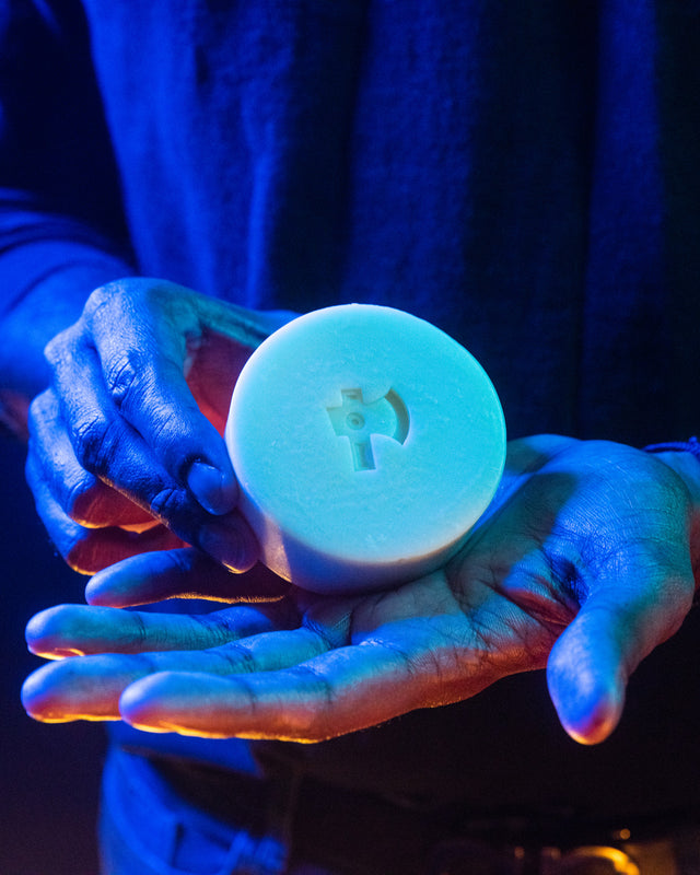 A person holding a Beardbrand Tree Ranger Utility Bar in their hands highlighted in vibrant lighting.