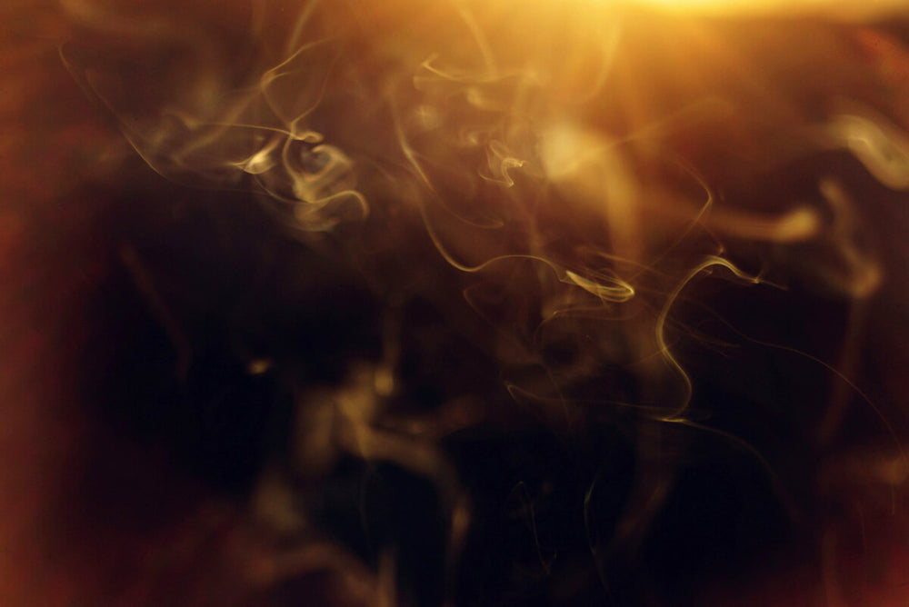 Soft golden light and swirling smoke patterns in a warm, hazy atmosphere, evoking a moody, vintage tone.