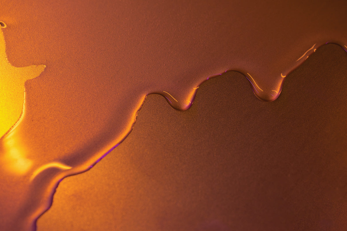 Oil dripping from top to bottom on a golden orange surface
