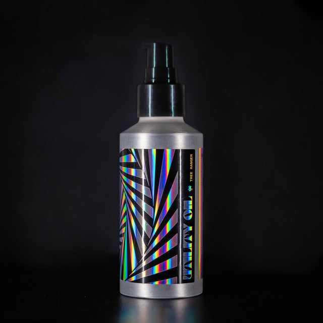 A bottle of Beardbrand Tree Ranger Utility Oil with a holographic label and black angular, radial pattern design.