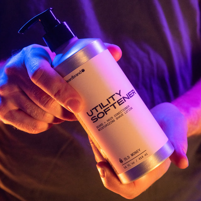 A person showing in their hands the front of Beardbrand Utility Softener in vibrant lighting.