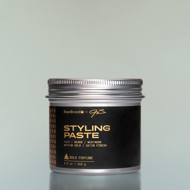 A container of Bold Fortune Styling Paste against a grey background.