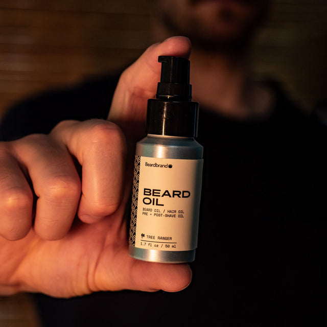 Beardbrand Tree Ranger Beard Oil bottle held in hand, natural grooming product for beard, hair, and post-shave care.