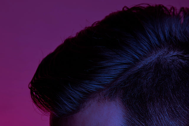 Close up of a white man's luscious, brown side-parted hair. 