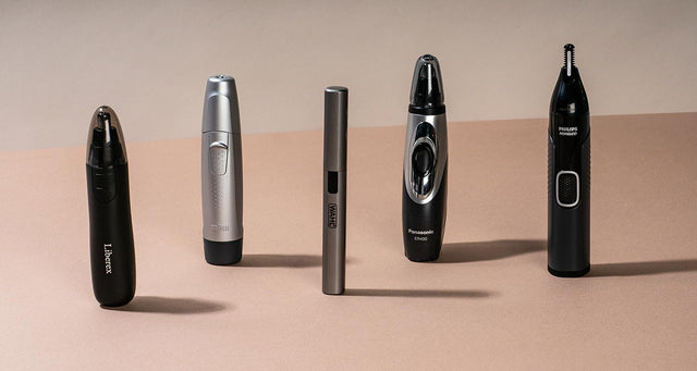 Five nose hair trimmers lined up on a pink table. 