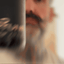 Bearded man applying Beardbrand Bold Fortune Cologne rollerball to his neck and showing the bottle.
