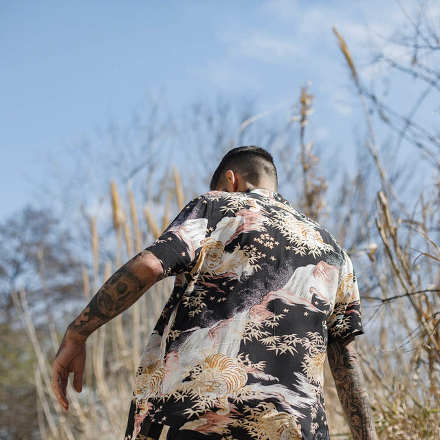 Carlos Costa wearing a patterned shirt in the wild, walking away through dried grasses.