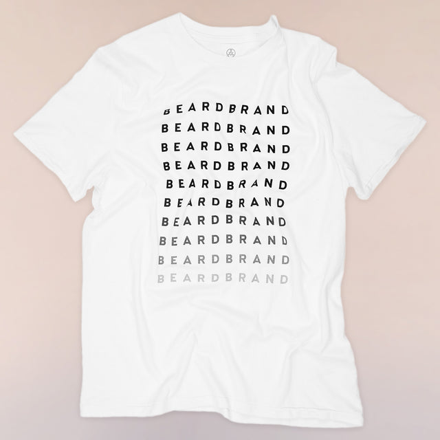 A white Beardbrand Forever Tee with "Beardbrand" in black ink at top repeated until fades to light gray on the front.