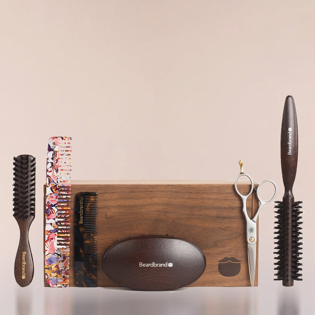 Beardbrand grooming tools lined up and leaning against a wooden Beardbrand Beardsman’s Box.