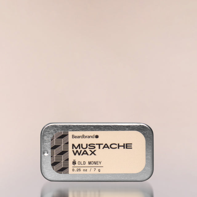 An Old Money Mustache Wax in an aluminum slide-open tray against a neutral background.