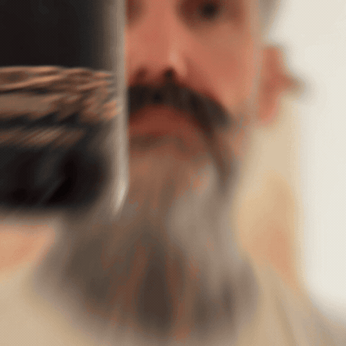 Bearded man applying Beardbrand Norse Winter Cologne rollerball to his neck and showing the bottle.