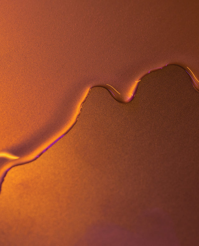 Oil dripping down metallic orange surface to show the texture.