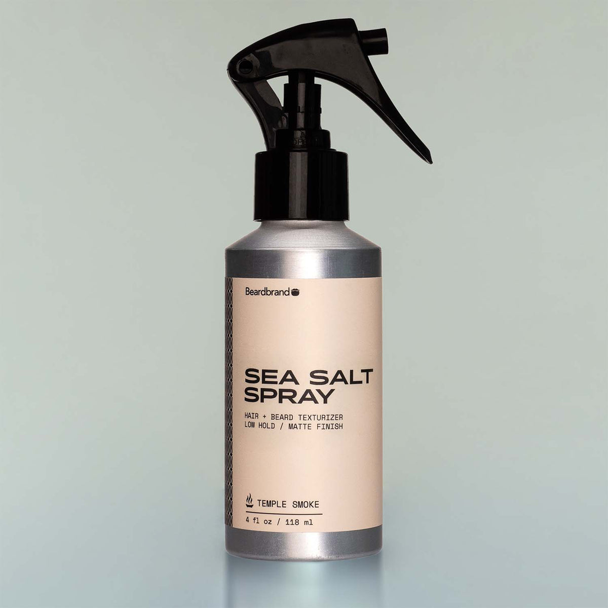 A bottle of Temple Smoke Sea Salt Spray with a sprayer dispenser against a grey background.