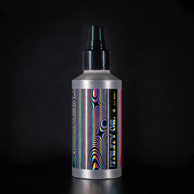 A bottle of Beardbrand Old Money Utility Oil with a holographic label and black wavy, psychedelic pattern design.