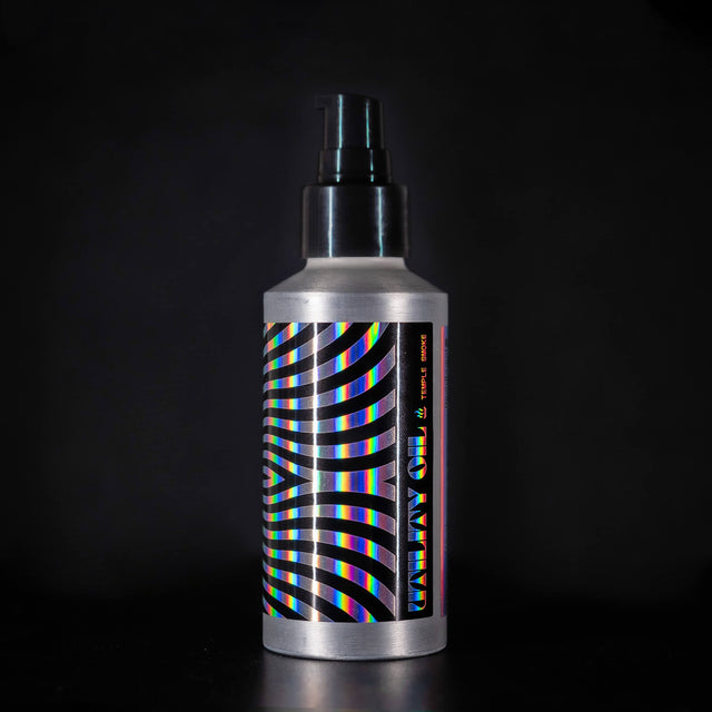 A bottle of Beardbrand Temple Smoke Utility Oil with a holographic label and black waved stripes pattern design.