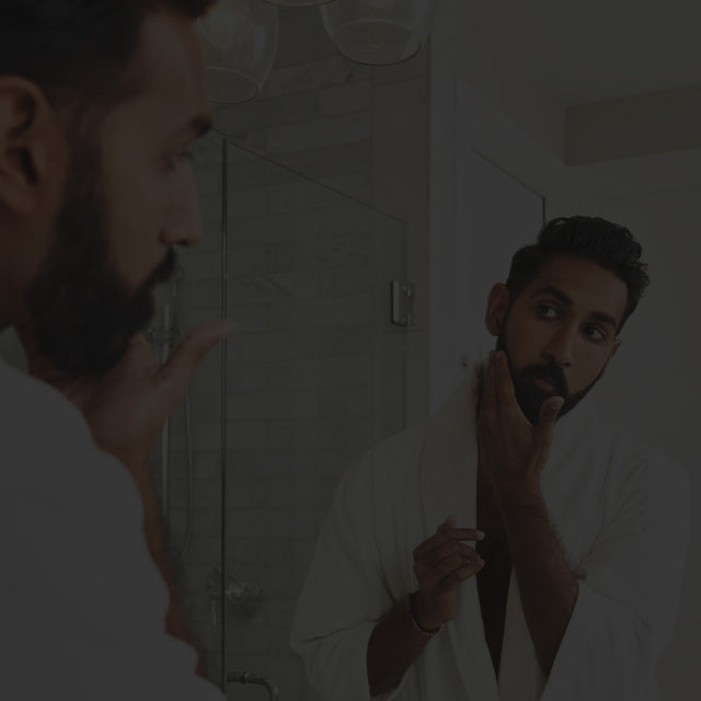 A beardsman getting ready in front of a mirror
