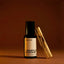 Beardbrand Temple Smoke eau de parfum bottle with palo santo wood on a warm brown background highlighting the fragrance’s smoky wood scent.
