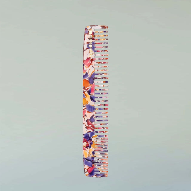 A Large Comb in Unicorn Vomit acetate standing upright against a grey background.